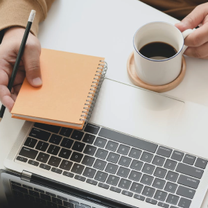 Woman taking notes and drinking coffee